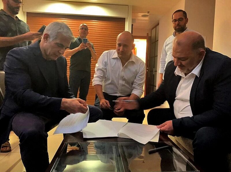 Mansour Abbas (R) signs a coalition agreement with Yair Lapid