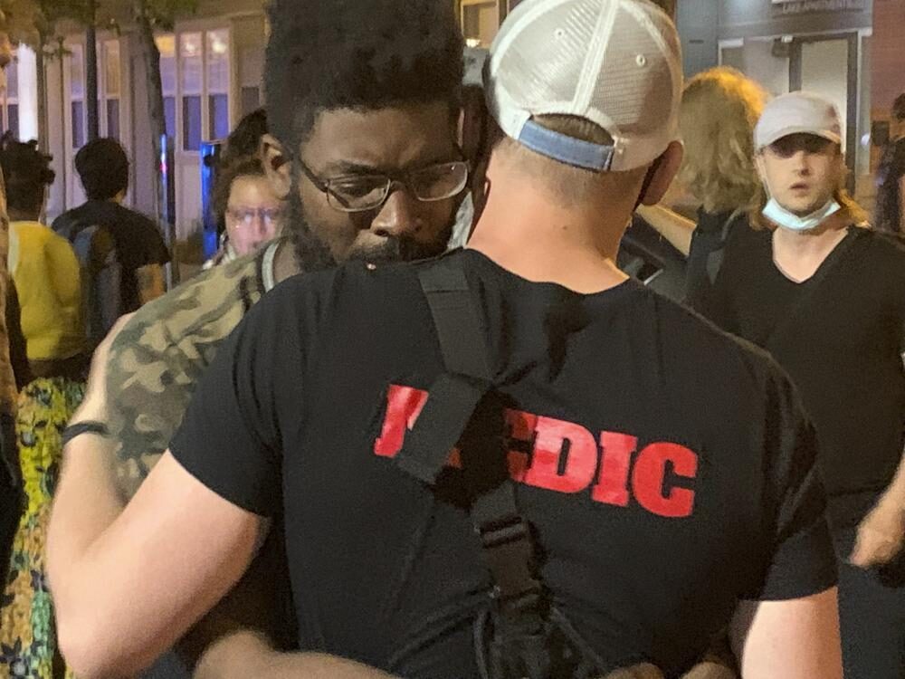 Click to enlarge A medic embraces activist D.J. Hooker