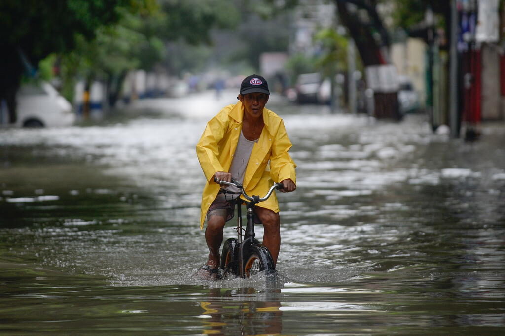 A man on a bicycle wades through a flooded