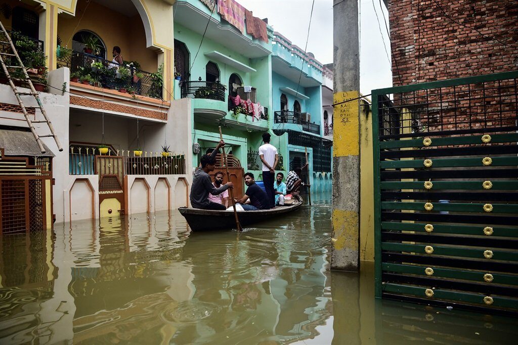 Residents use a boat to move in a flooded neighbourhood in Kareli Gaus Nagar area of Allahabad on 12 August, 2021 following heavy monsoon rainfalls that caused the overflowing of the Ganges and Yamuna Rivers.