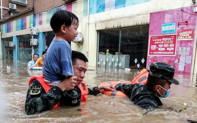 Rescuers evacuate a child from a flooded area after heavy rains in Suizhou, in China's central Hubei province