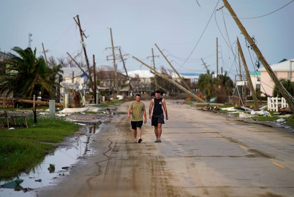 People walk through a neighborhood damaged by Hurricane Ida, Sept. 6, 2021, in Grand Isle, La.