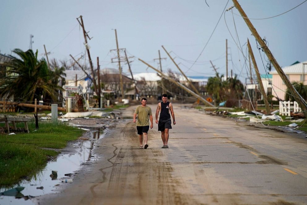Click to enlarge People walk through a neighborhood damaged by Hurricane Ida, Sept. 6, 2021, in Grand Isle, La.