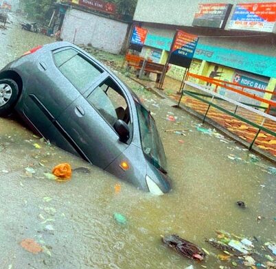 Click to enlarge A car stuck in an open manhole on the Outer Circular road.