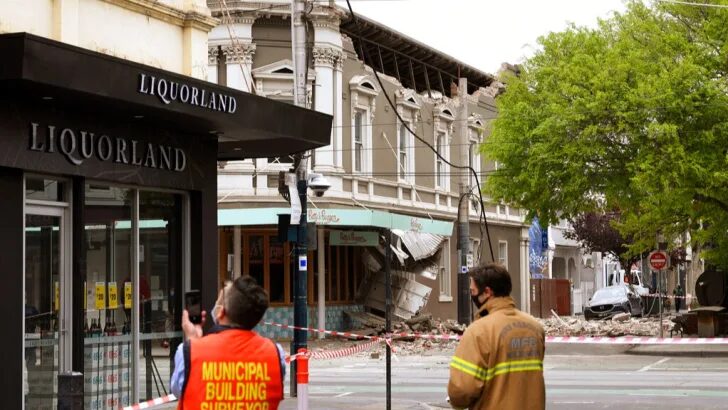 Click to enlarge Emergency workers survey damage in Melbourne, Australia, where debris is scattered after part of a wall fell from a building