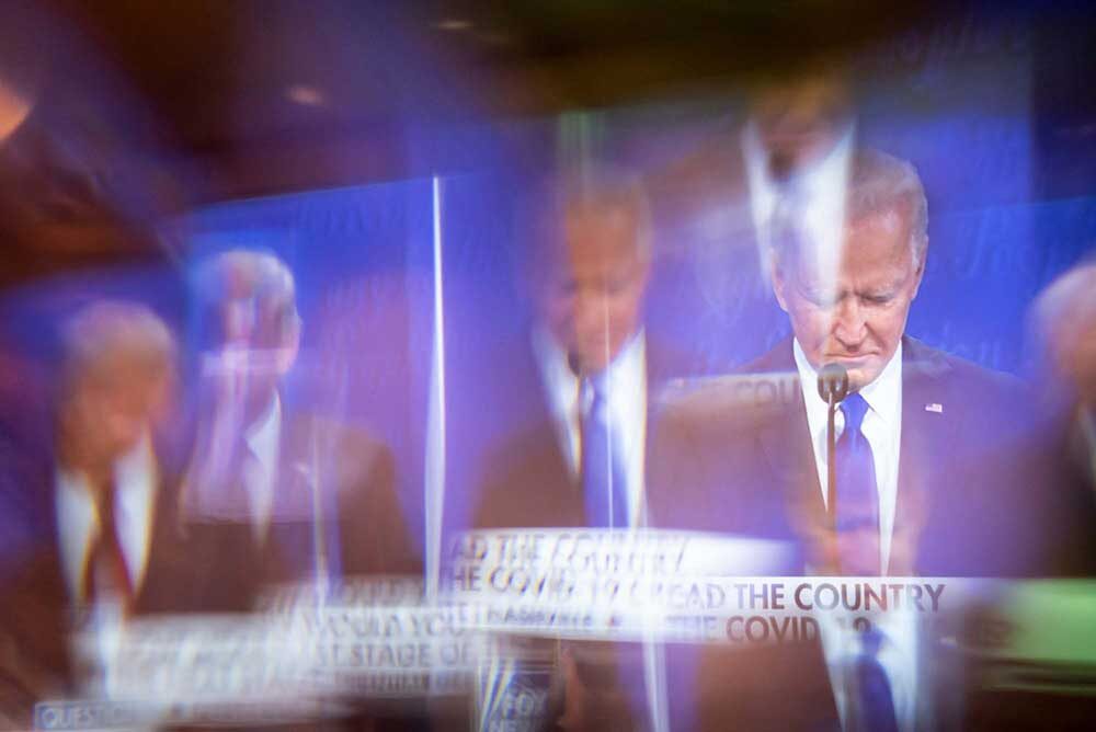 Joe Biden is seen on screen through a window
