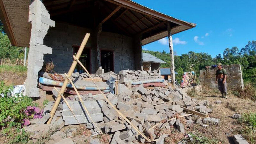 A man stands near his house damaged by an