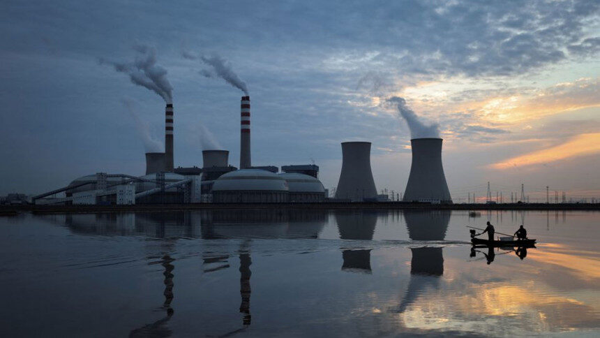 Fishermen sail a boat past a power plant of the State Development and Investment Corporation outside Tianjin, China on October 14.