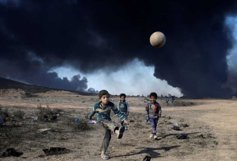Click to enlarge Boys play in front of burning oilfields in Qayyara, south of Mosul, Iraq, 2016.