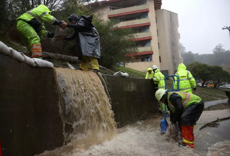 Workers try to divert water into drains as rain pours down on October 24, 2021, in Marin City, California.