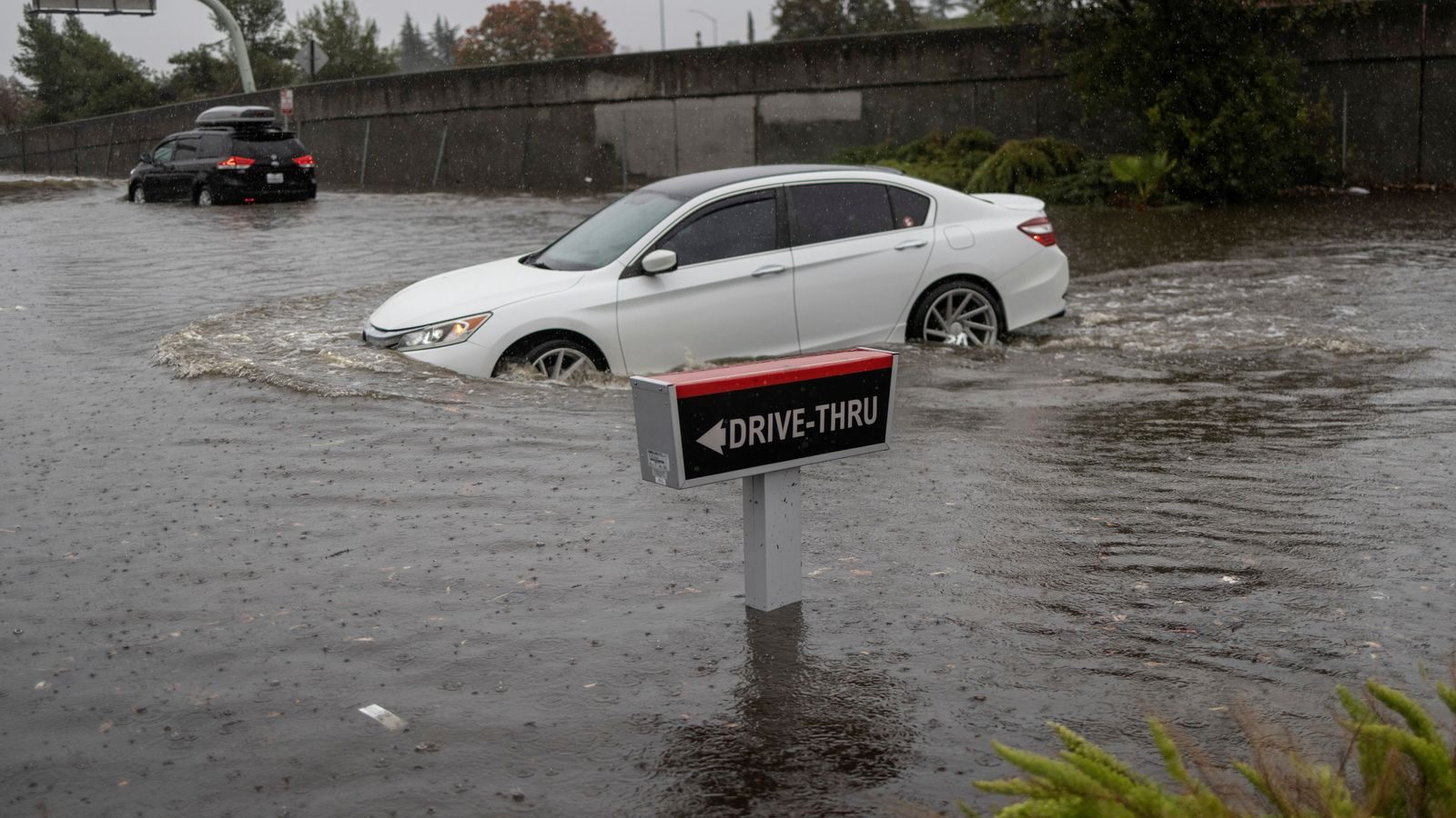 A vehicle drives through a flooded area