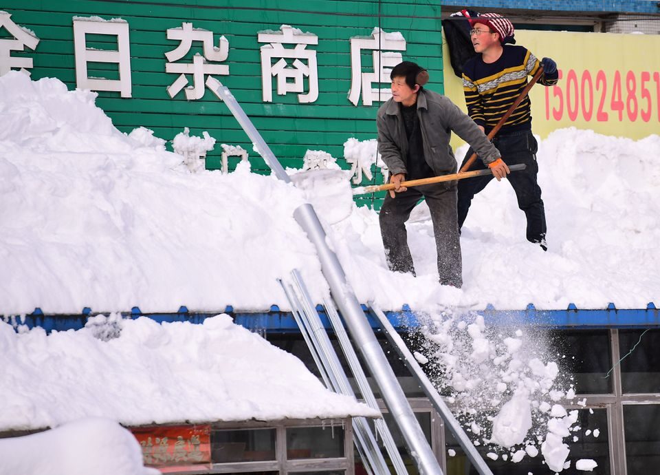 Click to enlarge Men clear snow from a roof following heavy snowfall in Shenyang, Liaoning province, China November 9, 2021. Picture taken November 9, 2021.