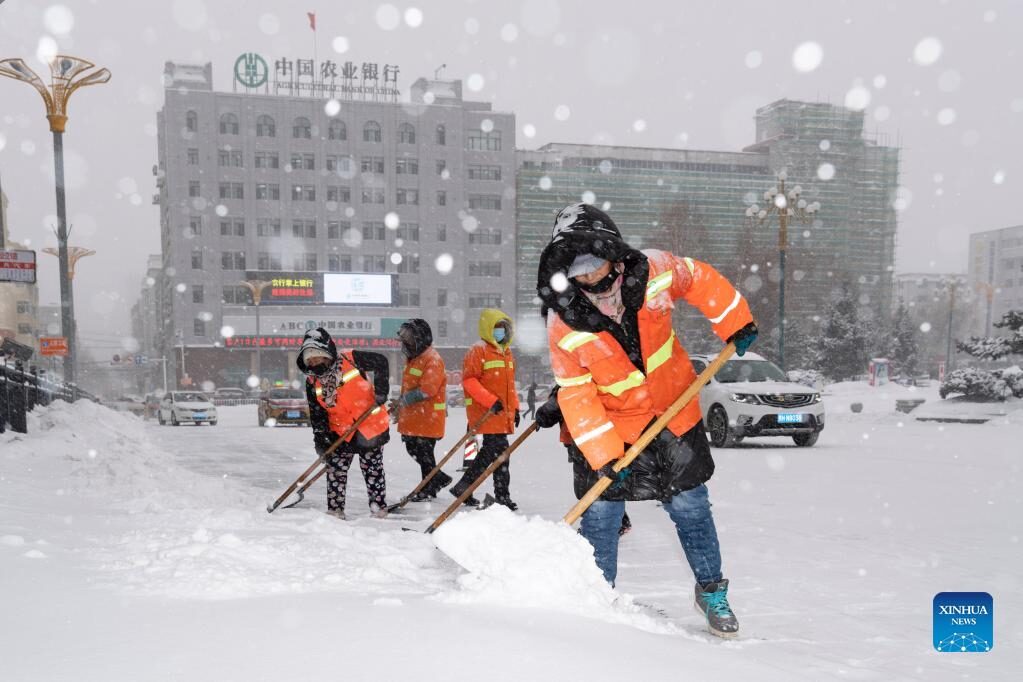 Sanitation workers clear snow from a street in Hegang City, northeast China