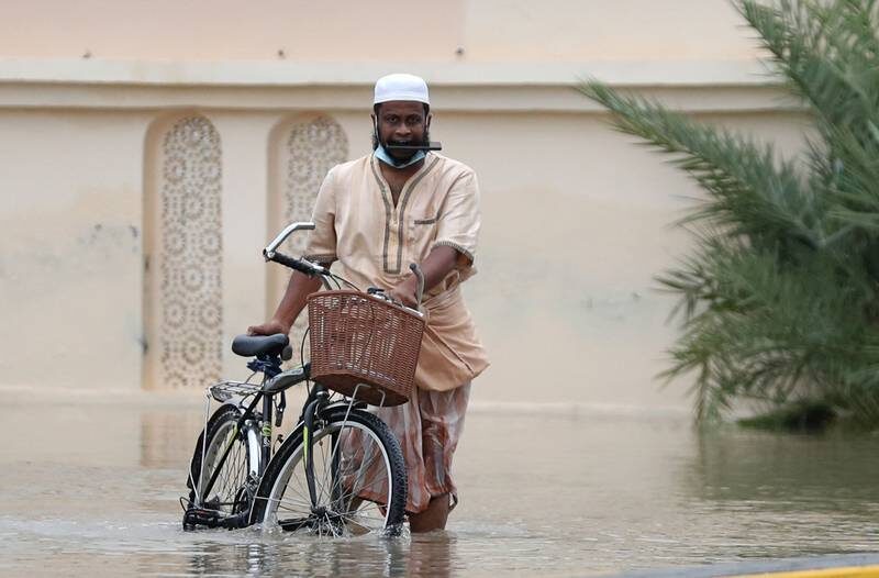 Click to enlarge A man wades through a flooded street in Oman