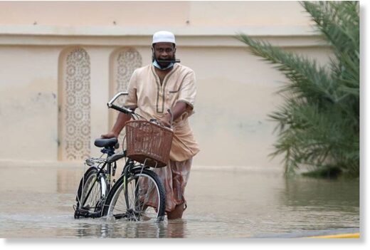 A man wades through a flooded street in Oman
