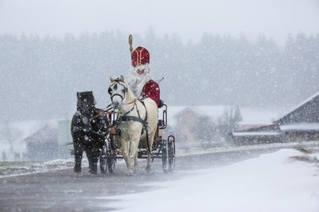 Click to enlarge A man dressed as 'Nikolaus' rides a horse-drawn
