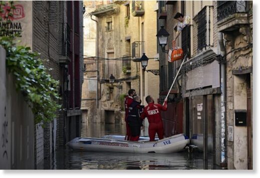 A rescue team help a woman in her home in a flooded area near the Ebro River in Tudela, northern Spain, Sunday, Dec. 12, 2021.