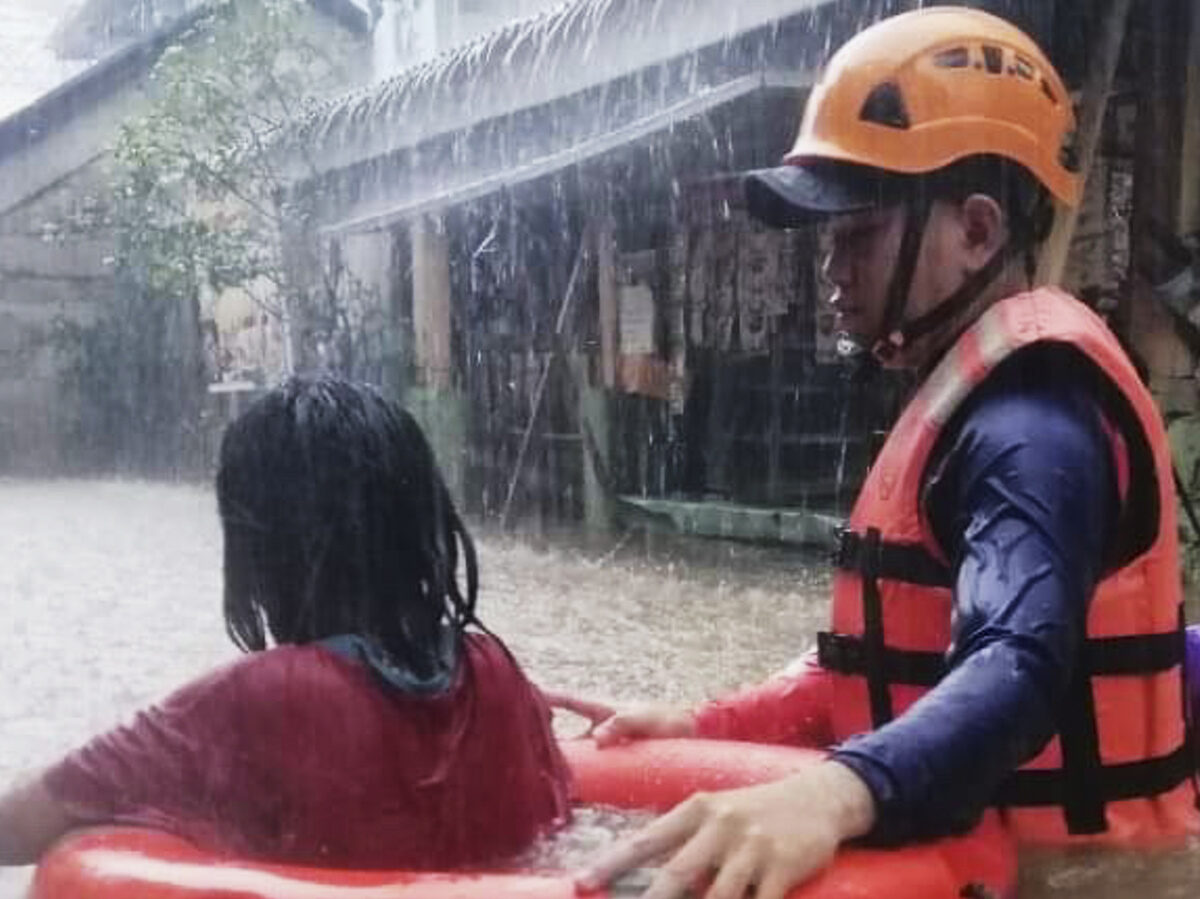 Rescuer assists a girl as they wade through flooding caused by Typhoon Rai in Cagayan de Oro City, southern Philippines on Thursday, December 16, 2021