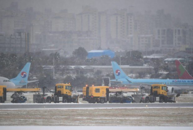 Click to enlarge Workers clear snow on runway at Jeju