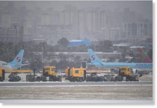 Workers clear snow on runway at Jeju
