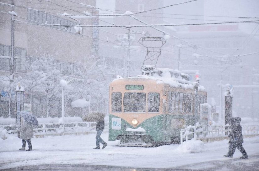 People cross a street in heavy snow in the city of Toyama, Toyama