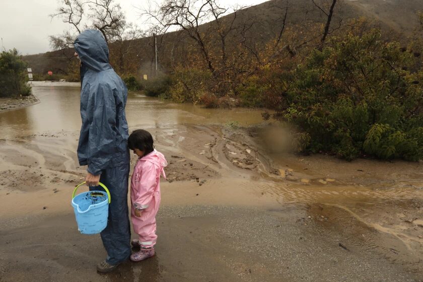 Mark Carrow and his granddaughter Ella Glass stand near a flooded section of the Leo