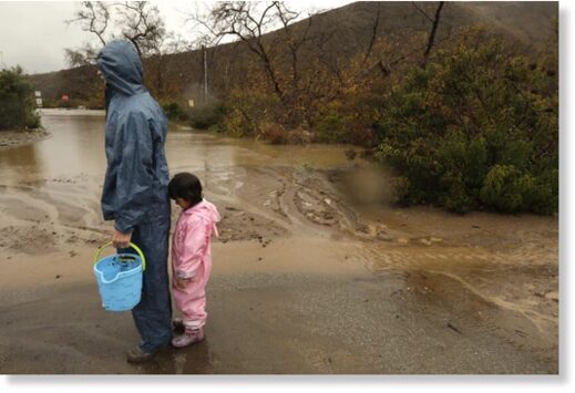 Mark Carrow and his granddaughter Ella Glass stand near a flooded section of the Leo