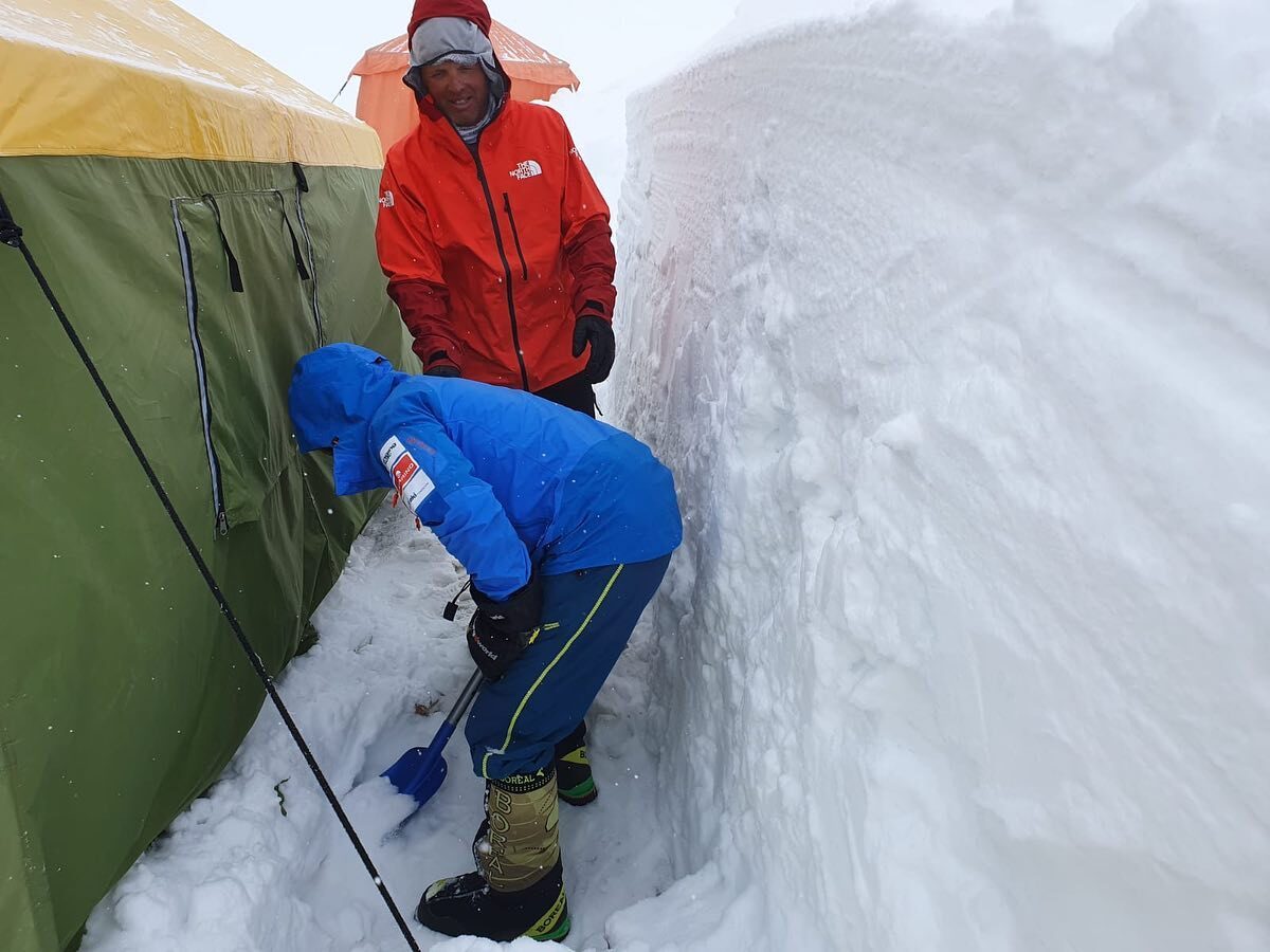 Simone Moro in red and a Nepali team member work on the deeply buried Manaslu BC tents.