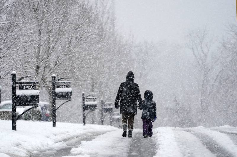People go for a walk as snow falls Sunday, January 16, 2022, in Nolensville, Tennessee.
