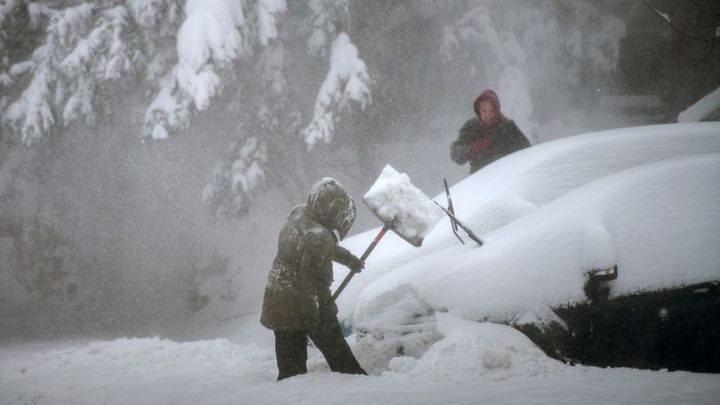 Click to enlarge People try to clear snow around their car in Stony Brook, New York, on January 29, 2022.