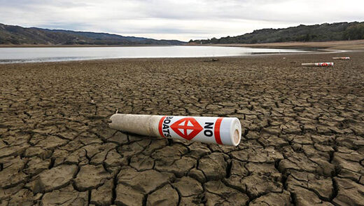 A warning buoy sits on the dry, cracked bed of Lake Mendocino