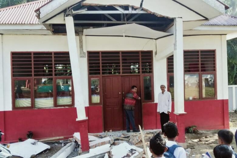 Click to enlarge Residents inspecting a damaged building after a 6.2-magnitude earthquake, in Kajai village in West Pasaman, Sumatra, on Feb 25, 2022.