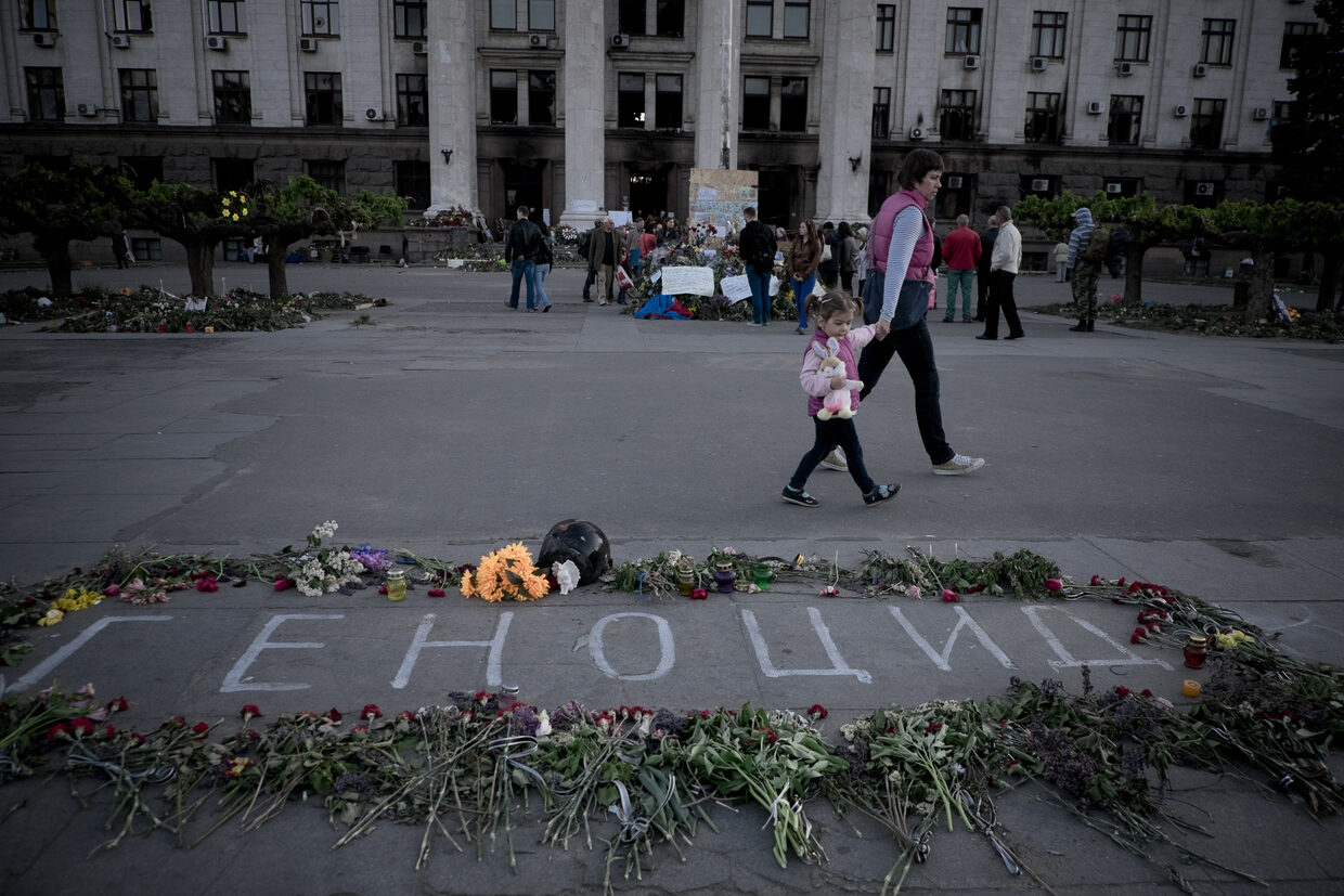 Flowers and the word 'Genocide' outside the burnt trade union building in Odessa
