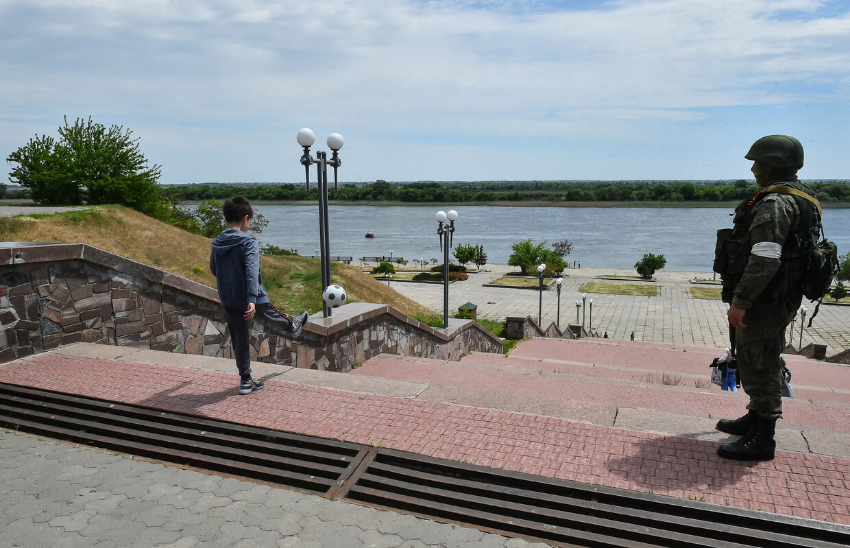 Click to enlarge Russian serviceman patrolling as a boy plays football