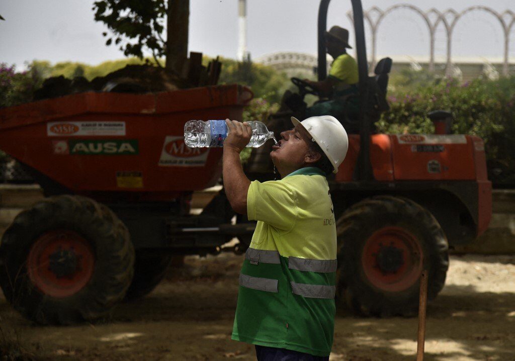 Click to enlarge A construction worker drinks water to fight the scorching heat during a heatwave in Seville on June 13, 2022.