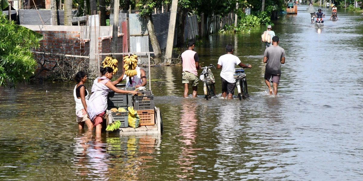 A vendor wades through a flooded street, in Kamrup distric of Assam, June 24, 2022.