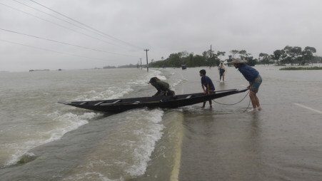 Two men and a kid are trying to float a boat