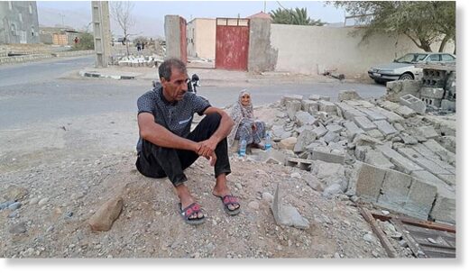 Click to enlarge People sit by the rubble amidst destruction in the aftermath of a 6.0 magnitude earthquake in Iran's southern Hormozgan province on 2 July.