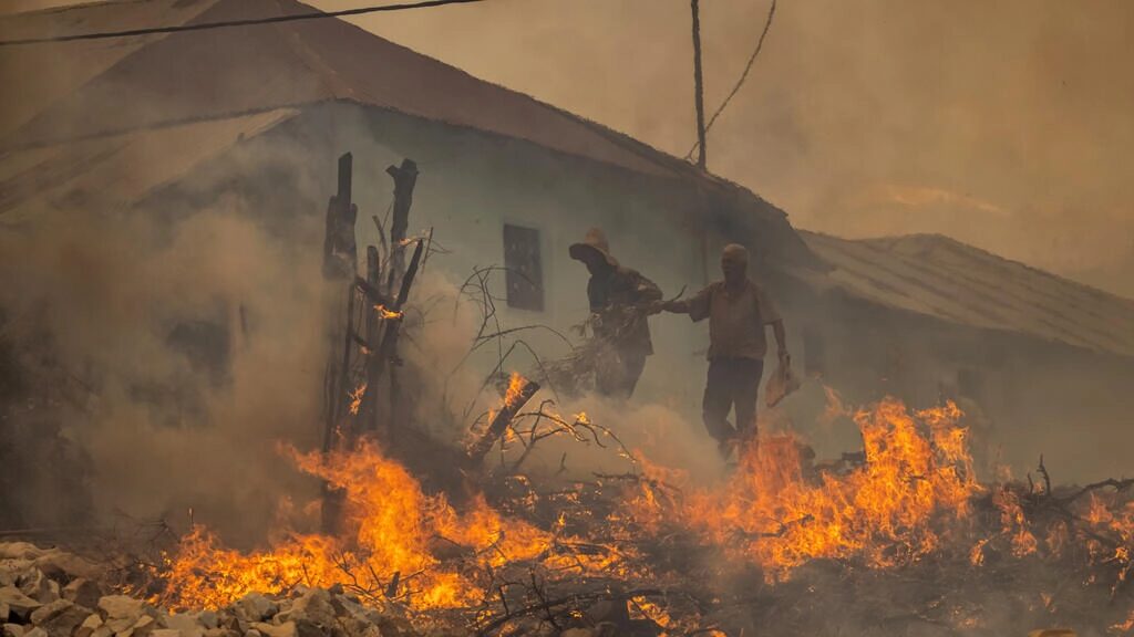 Two men evacuate from a village as forest fires rage near the Moroccan city of Ksar el-Kebir on Thursday