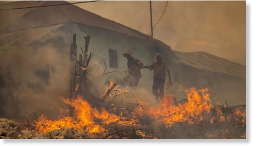 Click to enlarge Two men evacuate from a village as forest fires rage near the Moroccan city of Ksar el-Kebir on Thursday