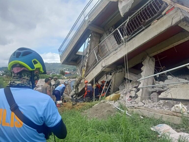 Click to enlarge Rescuers and policemen retrieve a resident from a collapsed building following an earthquake in the northern Philippines