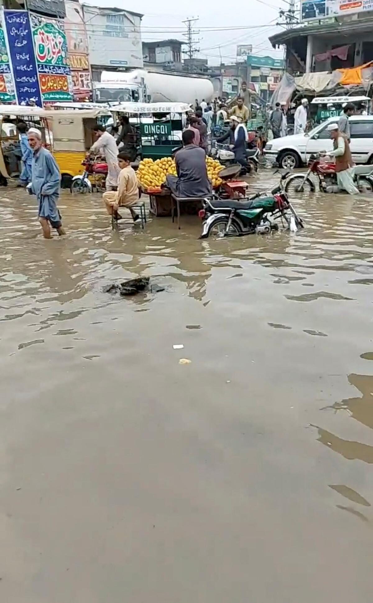 People and vehicles move around a flooded market in Charsadda, Pakistan on July 30, 2022 in this screengrab obtained from social media video.