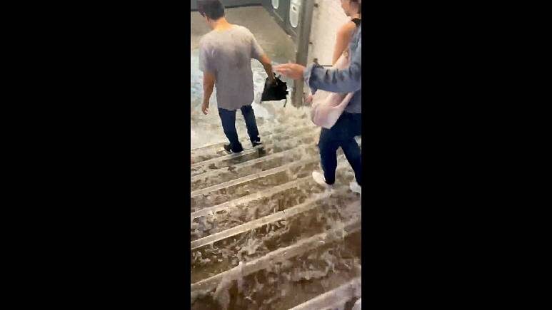 Click to enlarge People walk as water rushes down the stairs following a heavy rainfall at Victor Hugo metro station in Paris, France August 16, 2022