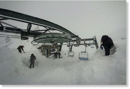 workers clearing the media platforms of snow so that they work correctly.