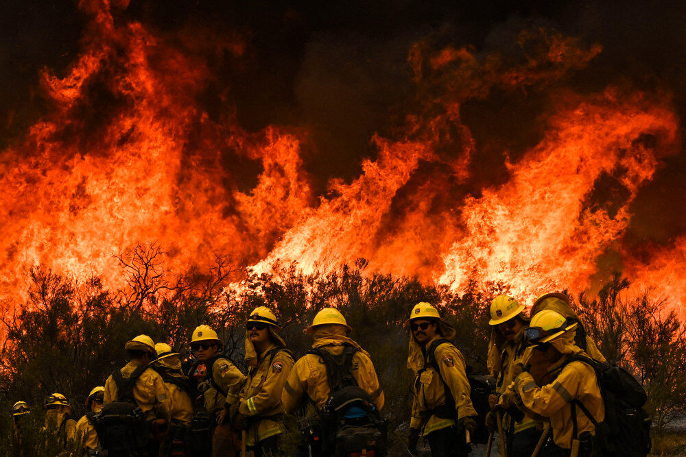 Cal Fire firefighters turn away from the fire to watch for stray embers during an operation to build a line to contain the Fairview Fire near Hemet, Calif., on Thursday.