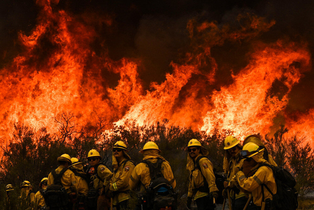Click to enlarge Cal Fire firefighters turn away from the fire to watch for stray embers during an operation to build a line to contain the Fairview Fire near Hemet, Calif., on Thursday.