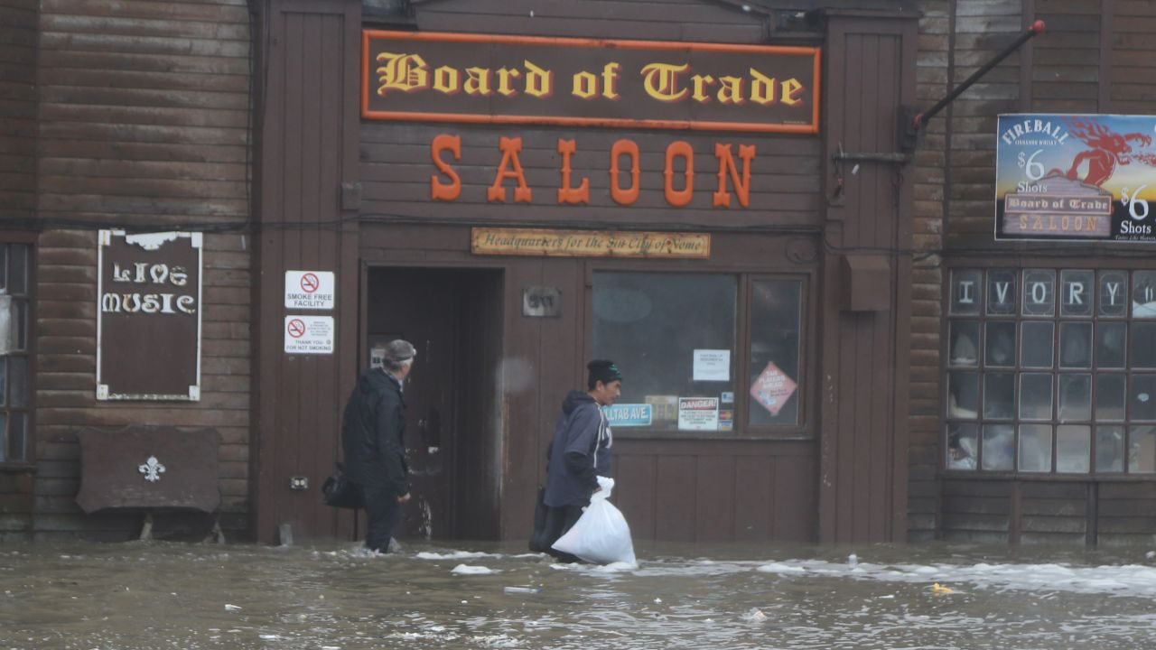 Click to enlarge Two men walk through rushing water on Front Street, just a half block from the Bering Sea, in Nome, Alaska, on Saturday, Sept. 17, 2022.