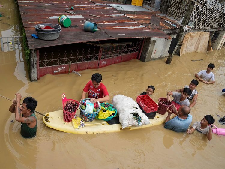 Residents give away onions and other foods along a flooded road due to Typhoon Noru (codenamed 