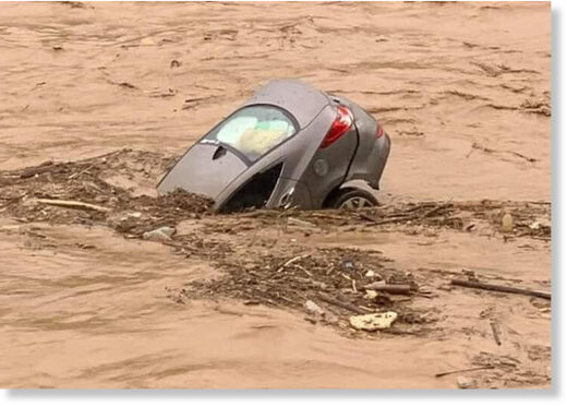 A car is half swallowed by floodwaters.