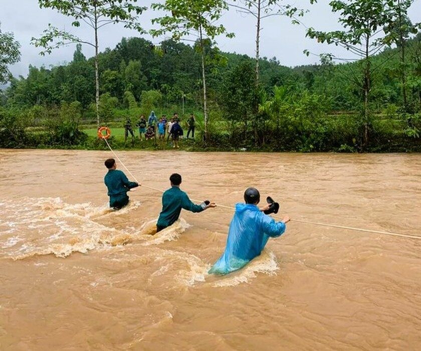 Military force crossing a stream with a rope to move people away from flooded areas to a safe place.